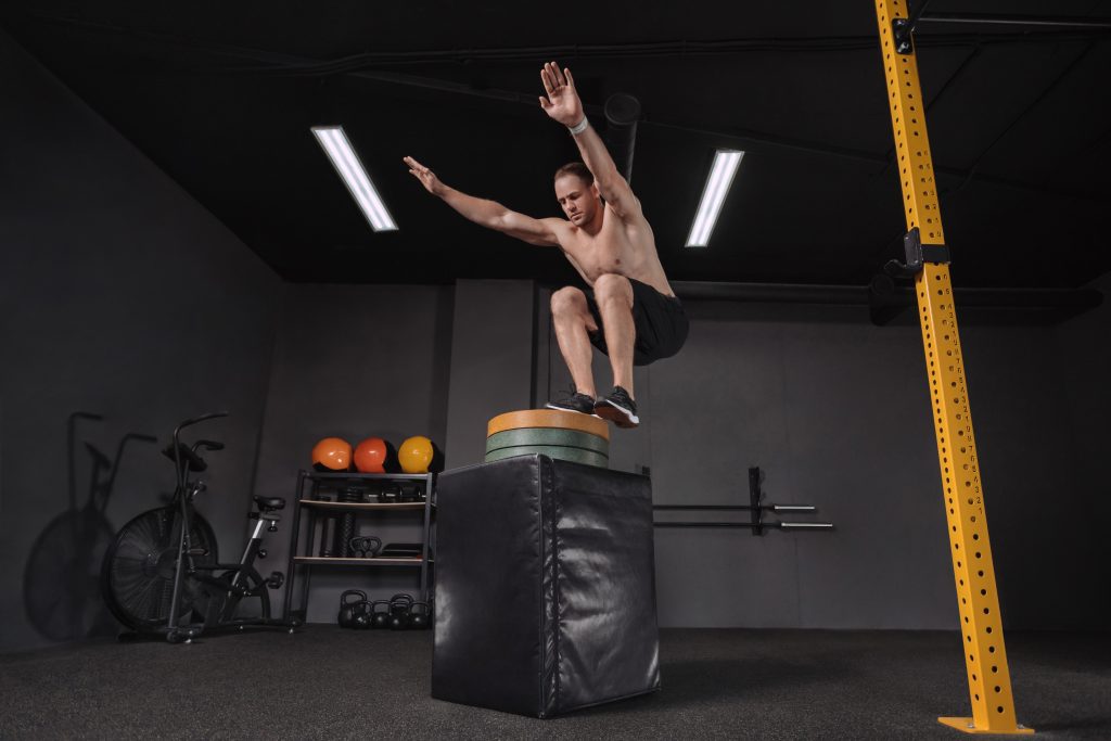 Crossfit athlete doing box jumping exercise at gym