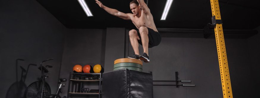 Crossfit athlete doing box jumping exercise at gym